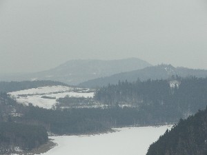 Dole v údolí zakázaná zóna zasněžené přehrady, na obzoru hora Vladař, koruna kraje